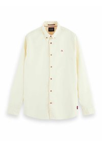 Crème kleurige longsleeve shirt met knoopsluiting aan de voorkant, bruine knopen en een klein rood logo op de borst. Zacht katoenen stof.