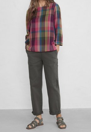 Multifarvet ternet bluse i nuancer af pink, grøn og blå, med trekvartærmer. Kombineret med grå bukser med opkrøllede manchetter og sandaler.