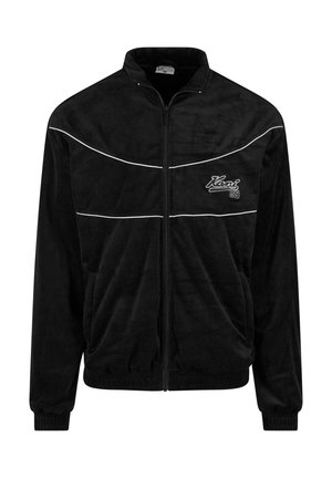 Sort zip-up jakke med en blød tekstur, der har to hvide vandrette striber og et logo på venstre bryst. Ribbet cuff og kant.