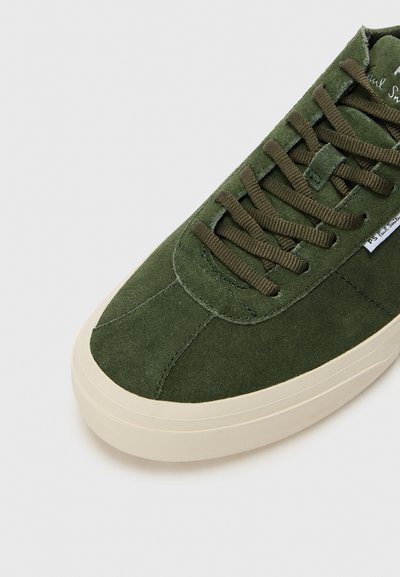 Adidași verzi din suede cu șireturi la față, suprafață texturată, vârf rotunjit și talpă din cauciuc de culoare crem. Include detalii cusute și branding.