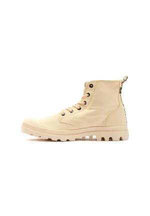 Bottines en toile beige avec une semelle en caoutchouc texturée, œillets en métal noir et une languette à l'arrière. Présente un design à bout rond.