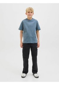 T-shirt en coton bleu clair avec des manches courtes et un col rond, accompagné de pantalons cargo noirs avec des poches latérales et des sneakers contrastants.