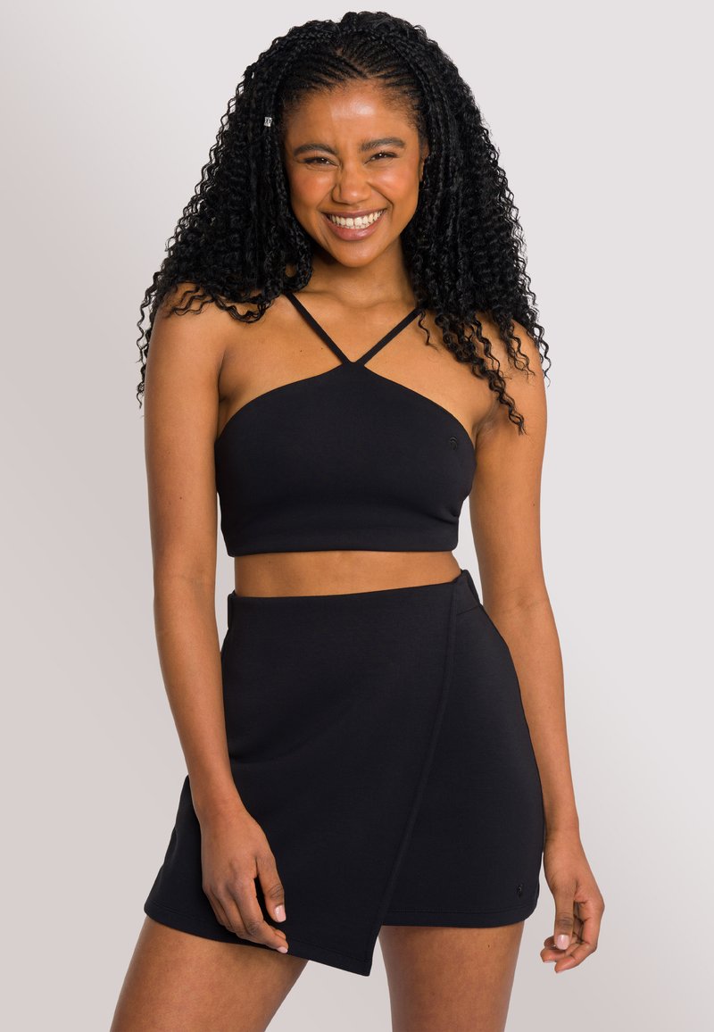 Czarny crop top z krzyżującym się paskiem i dopasowaną spódnicą o kroju owijanym. Wykonany z gładkiego, elastycznego materiału, z dopasowanym krojem.