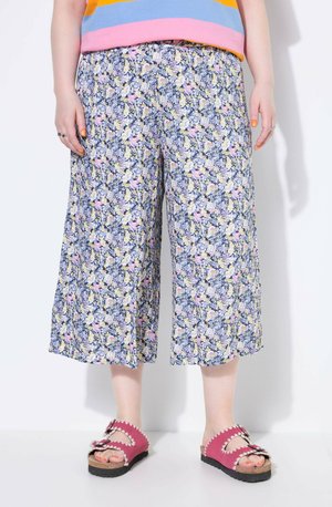 Culottes floraux bleus avec des fleurs roses et jaunes, présentant une coupe ample et une taille élastique ; accompagnés de sandales roses.