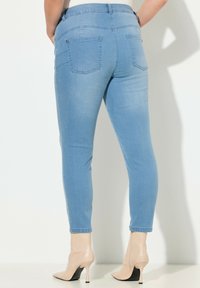 Vaqueros ajustados de color azul claro con una cintura alta, que cuentan con dos bolsillos traseros y un tejido vaquero liso y ligeramente elástico.