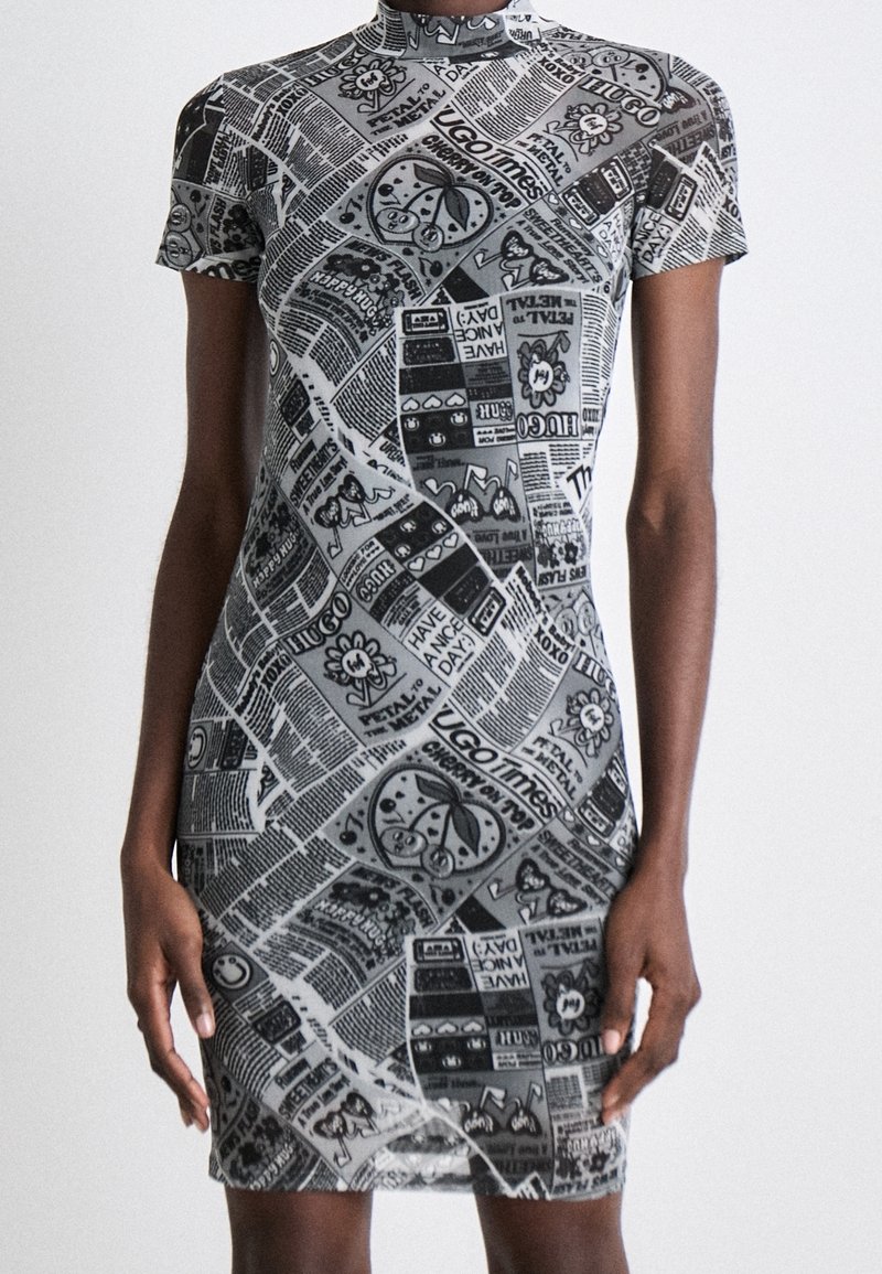Vestido ajustado en blanco y negro con un cuello alto, que presenta un estampado de gráficos al estilo de periódicos y motivos de dibujos animados. Mangas cortas y un diseño que realza la figura.
