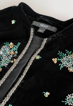 Schwarze Samtjacke mit dekorativen silbernen Perlen- und Paillettendetails an der Vorderseite, verziert mit grünen und goldenen Akzenten.