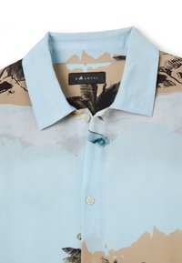 Camisa de manga corta con cuello azul claro y un estampado tropical, que presenta palmeras y montañas en tonos beige y azul. Incluye detalles de botones.