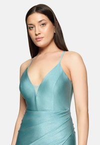 Robe en satin bleu sarcelle avec un décolleté plongeant en V et de fines bretelles. Le tissu a un léger éclat et est froncé à la taille pour un effet drapé.