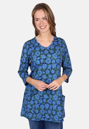 Blaue Blusentunika mit Dreiviertelärmeln, V-Ausschnitt und zwei Seitentaschen. Der Stoff hat eine weiche, strukturierte Oberfläche.