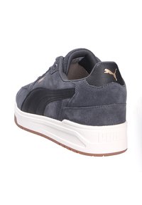Sneakers da uomo in suede grigio scuro con accenti in pelle nera, dotati di una suola intermedia bianca e una suola esterna in gomma marrone texture.