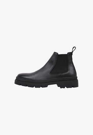 Bota Chelsea de cuero negro con panel lateral elástico, lengüeta en el talón y suela gruesa con tacos, mostrada de perfil sobre fondo blanco.