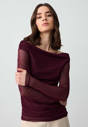 Top bordeaux con scollatura drappeggiata a spalle scoperte, maniche lunghe e trasparenti, e texture arricciata sul corpo. Tessuto liscio e leggero.