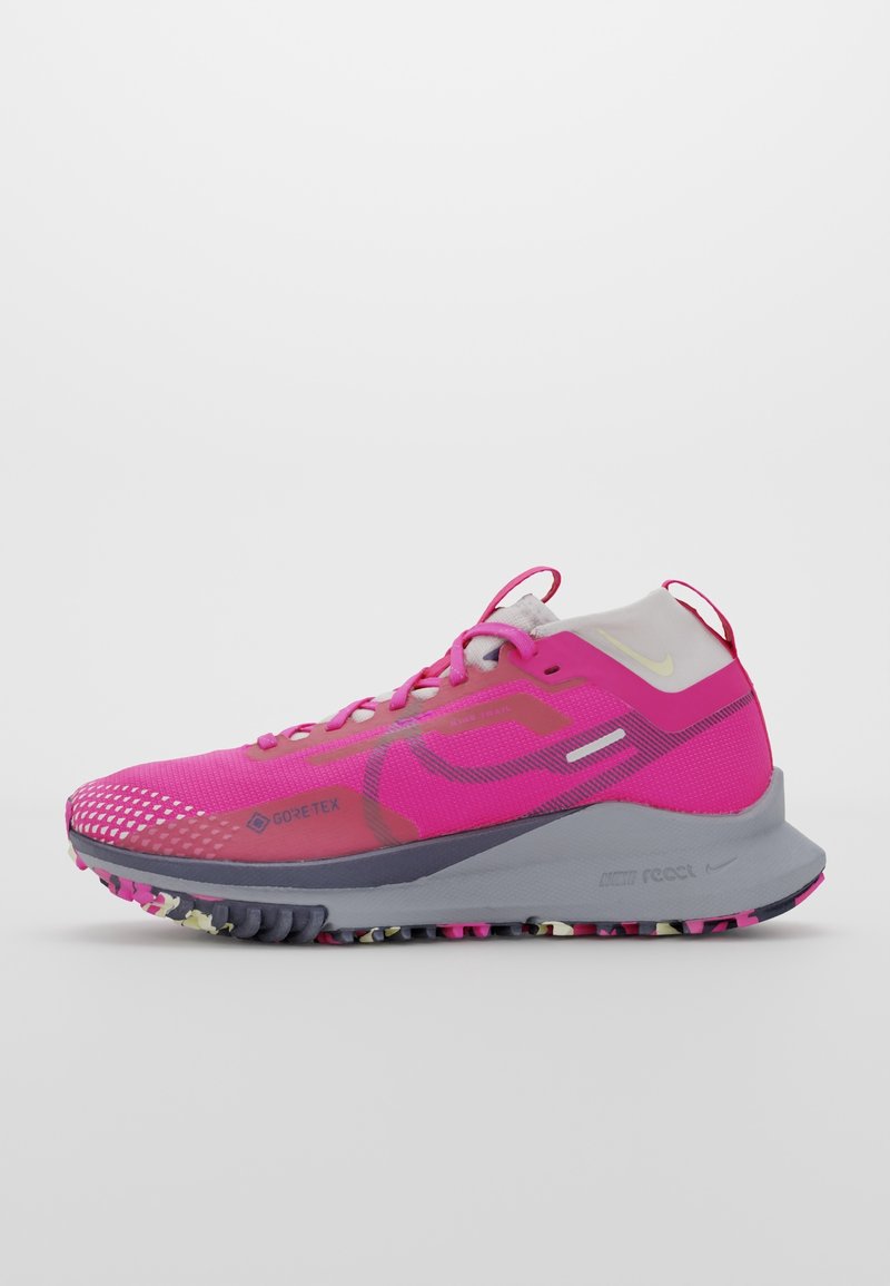 Chaussure de sport rose vif avec tissu GORE-TEX, semelle grise avec adhérence multicolore, col de cheville blanc et logos Nike réfléchissants.