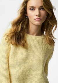 Maglione giallo lavorato a maglia con collo rotondo e maniche lunghe. Presenta una vestibilità ampia e un aspetto morbido e accogliente.