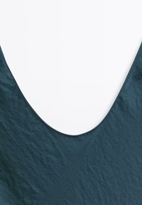 Abito color verde scuro con scollatura a V profonda, realizzato in un materiale testurizzato. Il tessuto ha una leggera lucentezza e una finitura liscia.