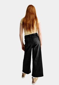 Zwarte spijkerbroek met hoge taille en wijde pijpen, met een klassieke vijf-pocket stijl en contrasterende witte stiksels.