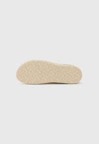 Sko såle, lys beige gummi med en teksturert, bølgete mønster. Jevn overflate og avrundet tå. Enkelt design, minimal detaljering.
