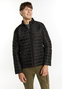 Geacă puffer neagră cu quiltig orizontal, guler �înalt, fermoar frontal și mâneci ajustate, purtată peste un pulover texturat gri.