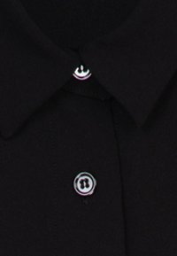 Chemise noire à col avec deux boutons noirs visibles, un près du col et un plus bas sur la patte de devant.
