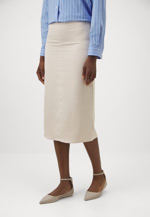Beige pencil skirt made of smooth fabric, with a form-fitting design and knee-length cut. Paired with light-colored flat shoes.