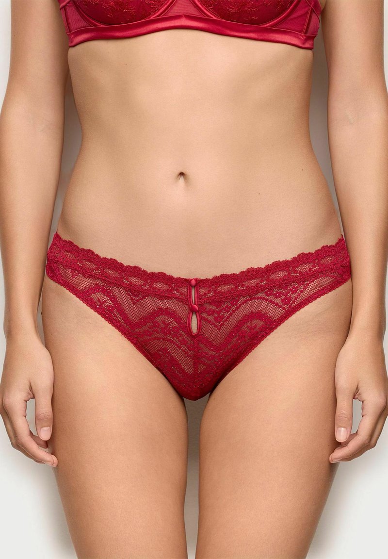 Røde blondertrusser med en bølget kant, et chevron mønster og en lille central sløjfe foran. Halvtransparent design.