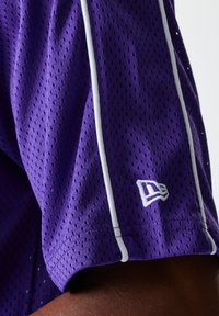 Jersey deportivo de malla púrpura con acentos blancos, que presenta un tejido transpirable, mangas cortas y un pequeño logo bordado en el dobladillo.