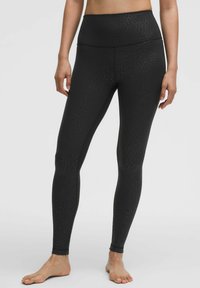 Zwarte, rekbare legging met een subtiele luipaardprint, hoge tailleband, aansluitend ontwerp en enkel-lange snit. Zachte, gladde stoftextuur.