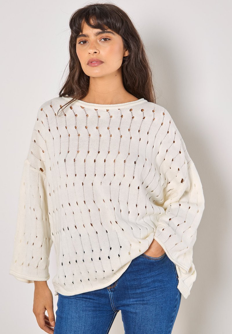 Gestrickter Pullover in Off-White mit lockerer Passform, weiten Ärmeln und strukturiertem Muster mit kleinen Öffnungen und farbigen Akzenten.