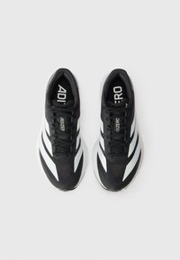 Baskets de sport noires avec une tige en mesh texturée, des rayures blanches sur les côtés et des lacets noirs. Le design présente une semelle légère.