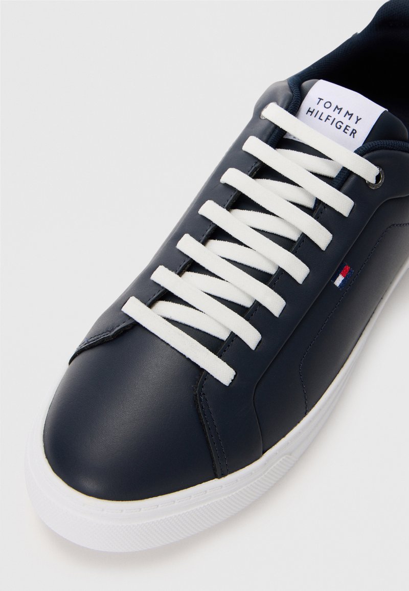 Navy leather sneaker with white laces and rubber sole. Features a logo tag on the tongue and textured accents on the upper.