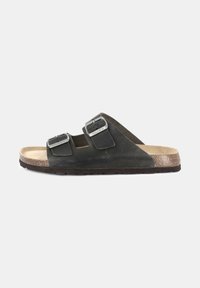 Sandali neri in pelle con doppia fibbia, soletta in sughero e suola in gomma texturizzata. Design aperto sulla punta con forma curva.