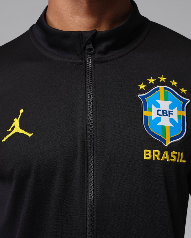 Chaqueta negra con cremallera, con escudo de fútbol de Brasil, cinco estrellas encima y logo amarillo de Jumpman en el pecho.