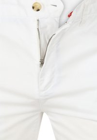 Witte katoenen broeken met een ritssluiting aan de voorkant en een messing knoopsluiting. Gladde textuur en geen zichtbare patronen of accenten.