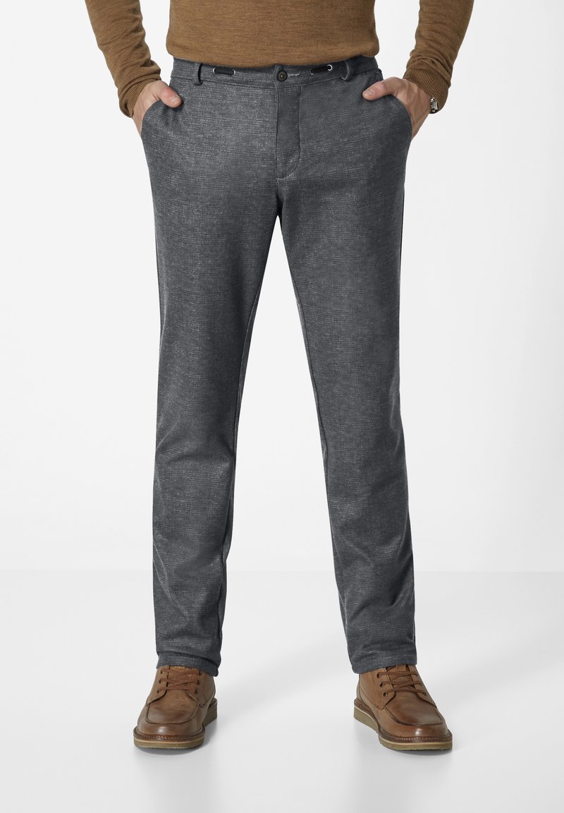 Dunkelgraue, strukturierte Hose mit geradem Schnitt, ausgestattet mit einem vorderen Knopfverschluss und seitlichen Taschen, kombiniert mit braunen Lederschuhen.