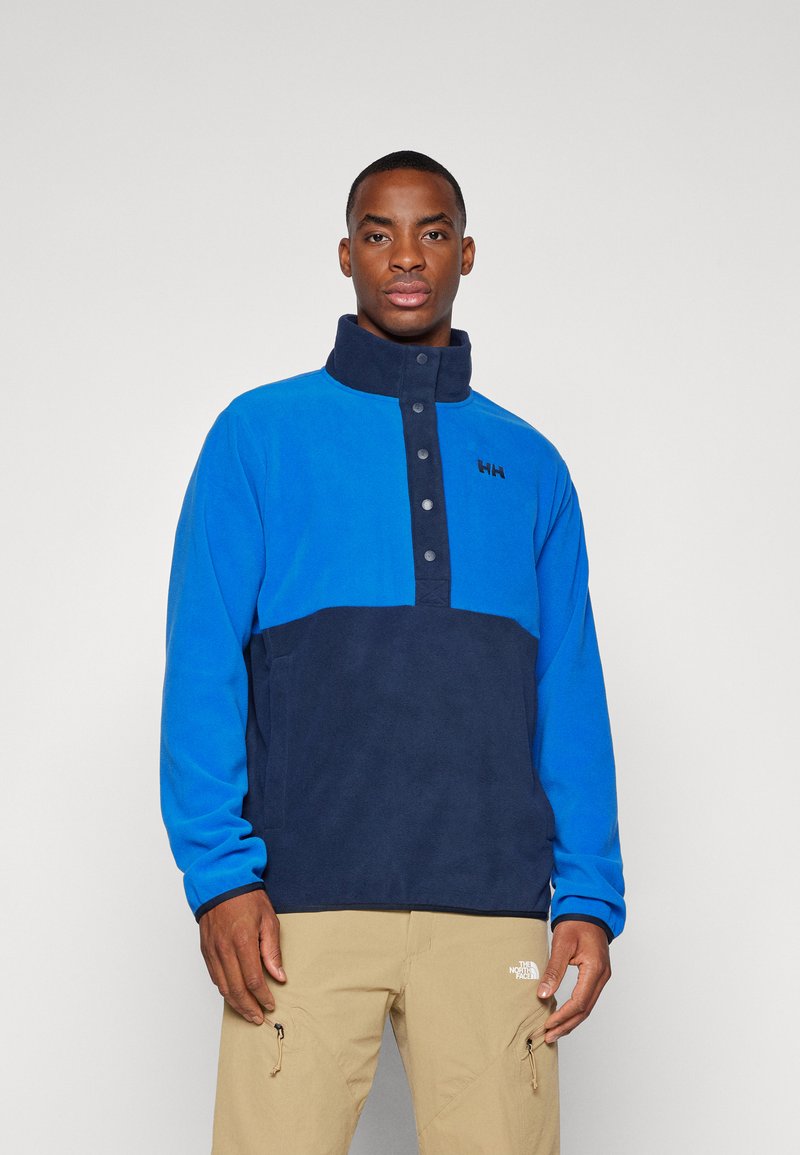 Blauer und marineblauer Fleece-Pullover mit hohem Kragen, vier Knopf-Leiste und einem Logo auf der Brust. Weicher Stoff und lockere Passform.