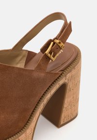 Rudi zomšo slingback batai su kamščio kulnu. Yra auksinė sagtis ir tekstūruotas dizainas. Uždara nosis su lygiu vidiniu pamušalu.