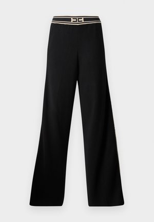 Pantalones de pierna ancha negros con una cintura en contraste beige que presenta un logo. Están hechos de una tela suave, mostrando un diseño fluido.
