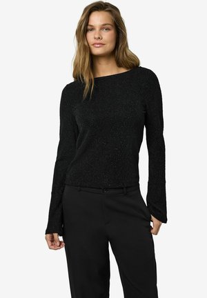 Schwarzes Langarmshirt mit strukturiertem Finish, mit Rundhalsausschnitt und lockerer Passform, kombiniert mit schwarzen Hosen.