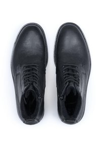 Czarne skórzane buty o gładkim wykończeniu, z wiązanym zapięciem, detalami zamka błyskawicznego oraz wyściełanym kołnierzem dla większego komfortu. Płaska podeszwa.