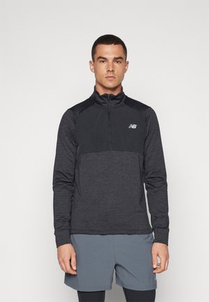 Tricou sportiv negru cu mânecă lungă, cu fermoar până la un sfert, dintr-un material texturat și cu un panou superior solid contrastant. Are un logo mic pe piept.
