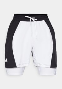 Pantalones cortos deportivos en blanco y negro con un cuerpo blanco texturizado y paneles laterales negros, que cuentan con una cintura con cordón y pantalones cortos interiores.