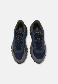 Scarpe da ginnastica navy e grigie con tessuto testurizzato, dotate di punta rinforzata, colletto imbottito, suola robusta e dettagli beige a contrasto.