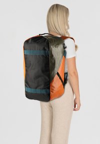 Mochila con paneles en naranja, negro y verde oliva. Cuenta con tela texturizada, correas ajustables y una forma rectangular elegante.