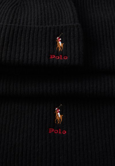 Melnā ribota adīta cepure ar brūnu polo spēlētāja logotipu un sarkano teksta uzrakstu "Polo" zem dizaina.