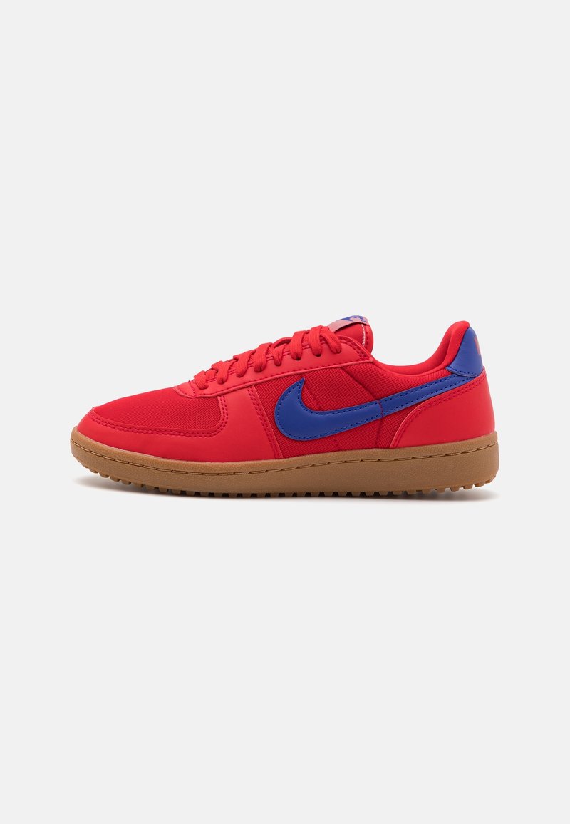Basket basse rouge avec le logo Nike bleu et semelle en gomme, vue de côté extérieur sur un fond clair uni.