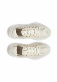 Baskets de sport beiges avec une tige en tricot texturé, des lacets élastiques et une semelle blanche rembourrée comportant de subtils accents de marque.