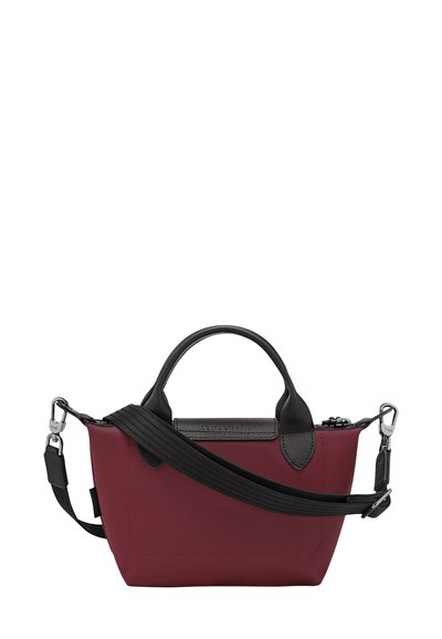 Maroon handbag with black leather accents, carrying handles, and a removable black strap. Textured fabric with a zipper closure.