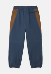 Μπλε και καφέ παντελόνια με στενή εφαρμογή, ελαστική μέση, πλαϊνές τσέπες και αντίθετες λεπτομέρειες. Κατασκευασμένα από ελαφρύ, αεριζόμενο ύφασμα.