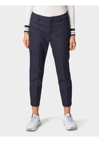 Granatowe spodnie w kratkę o wąskim kroju, charakteryzujące się gładką fakturą, subtelnym wzorem kraty, kieszeniami z przodu i dopasowanymi kostkami. Połączone z białymi sneakersami.